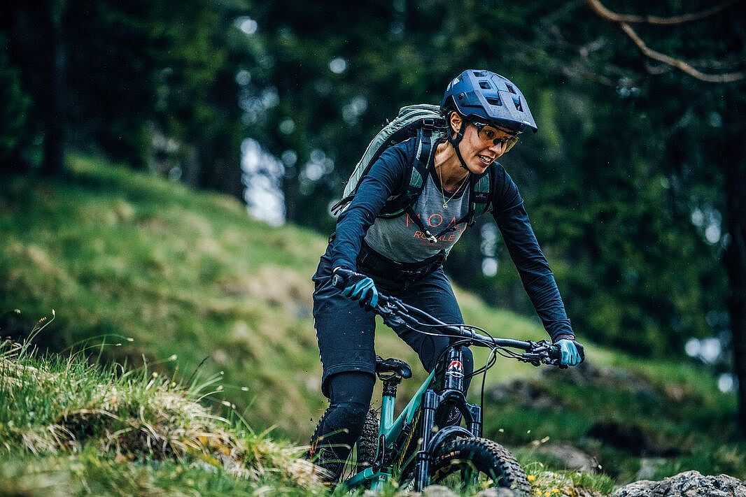 Mountainbike-Helm Frau auf einem Mountainbike im Wald mit Helm